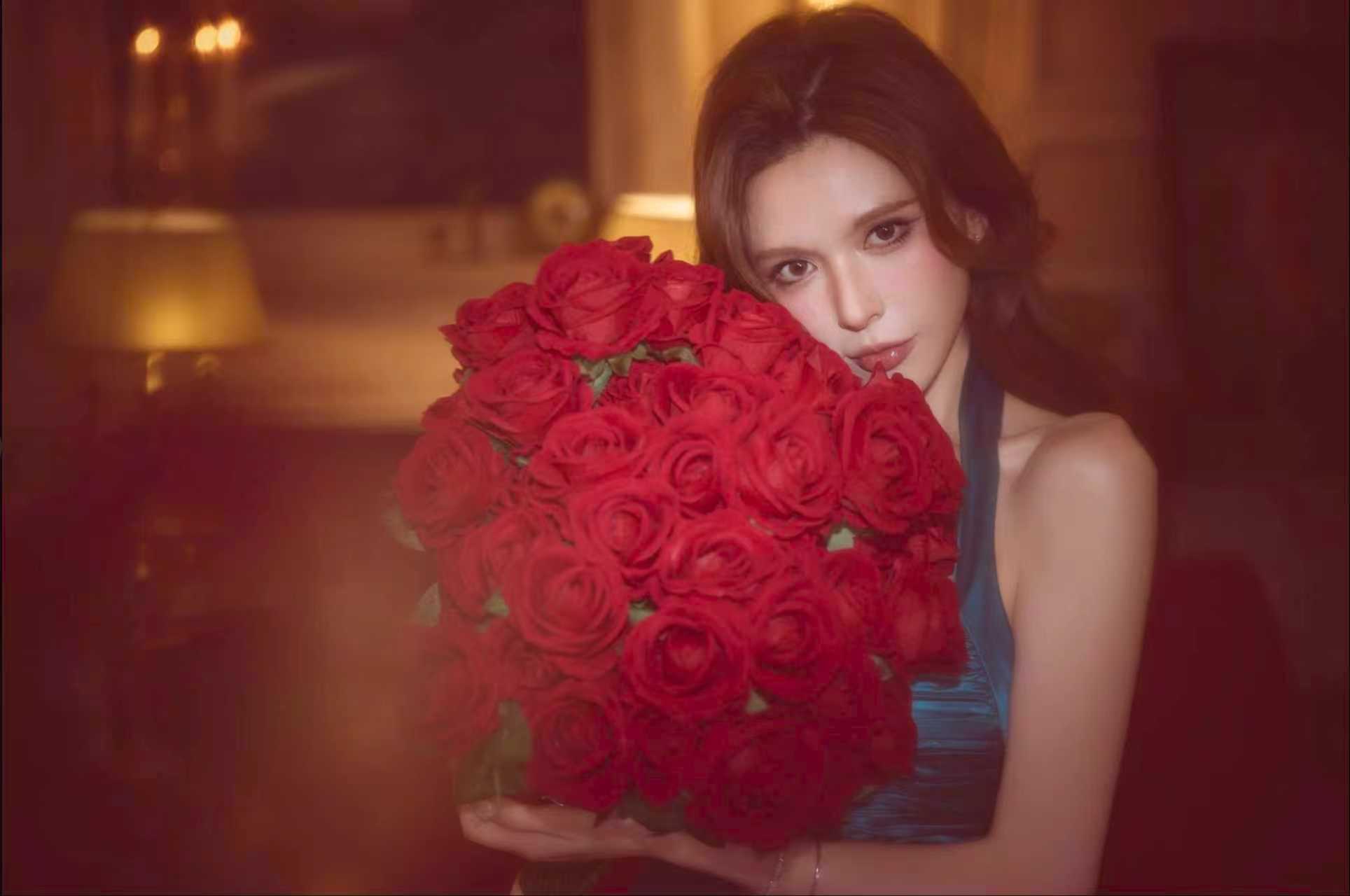 Vivi Rose holding a bouquet of red roses